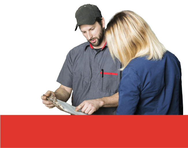 A close-up of an auto mechanic wearing a gray polo shirt and a cup pointing at a list on a clipboard and explaining to the customer