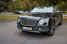 A front view of a black bently on a parking lot.
