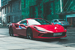 A side view of a red Ferrari on a side walk.